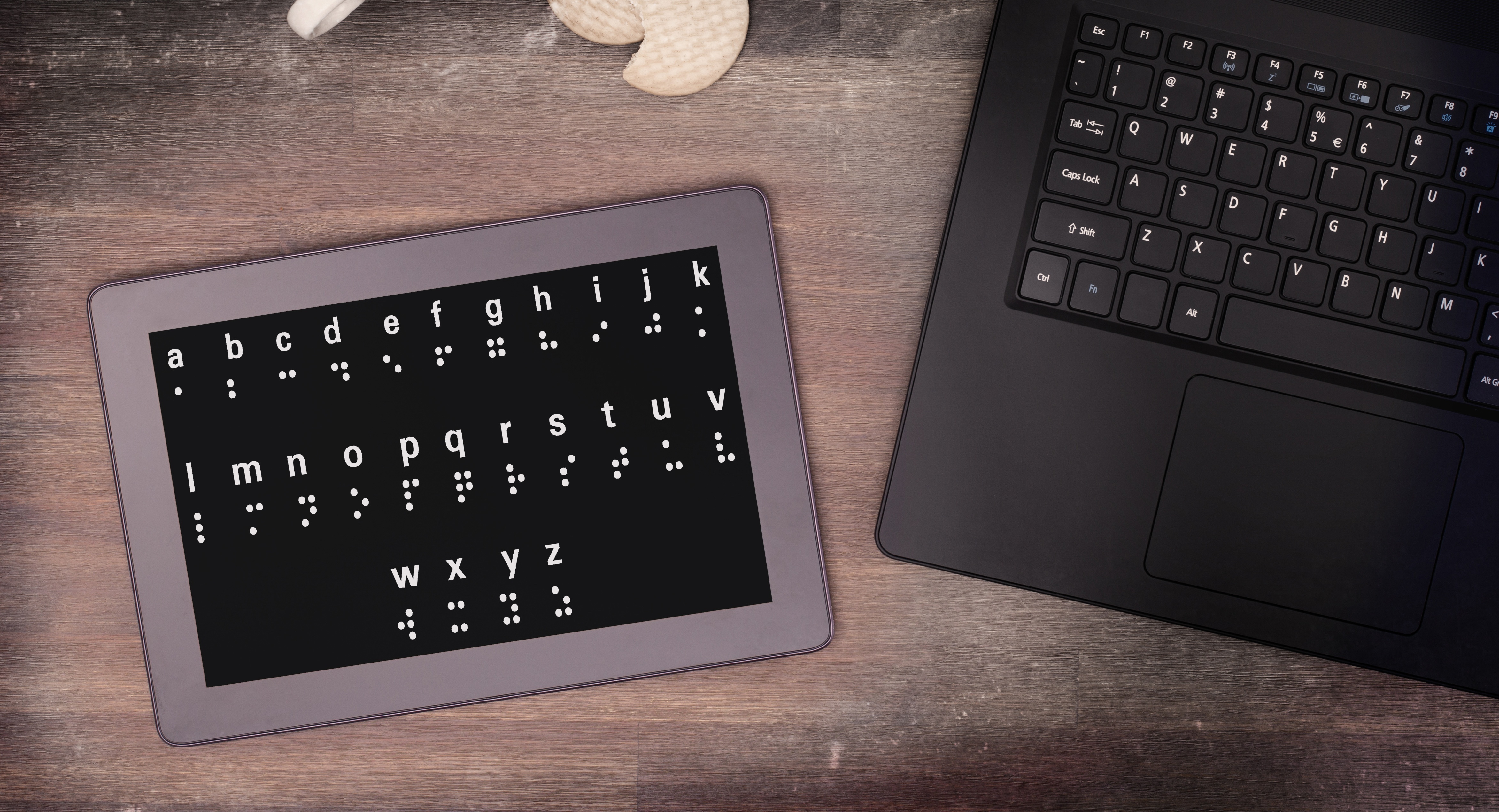 A braille keyboard on a desk next to a standard laptop